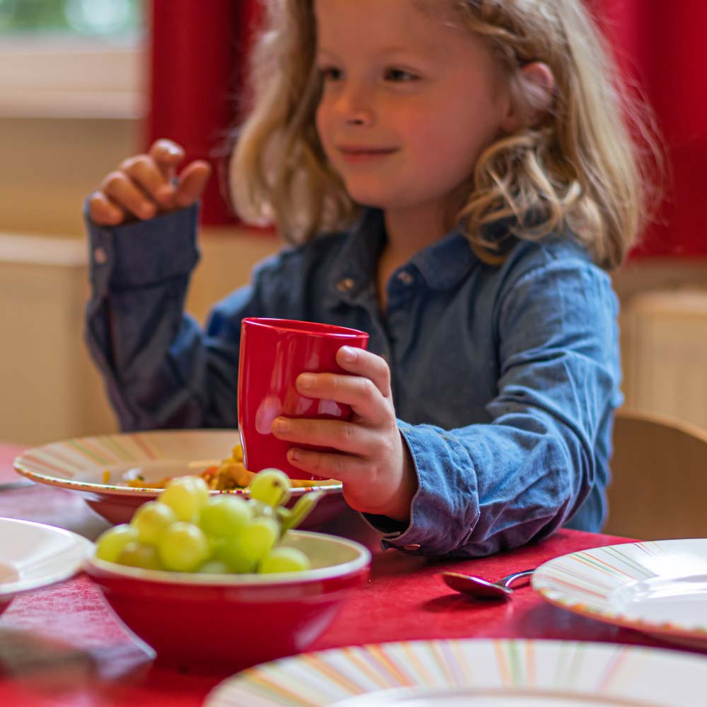 Ein Kind in der Kita trinkt aus einem ORNAMIN Mehrweg Kinderbeher
