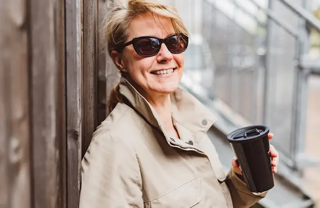 Lächelnde Frau mit ORNAMIN Mehrwegbecher