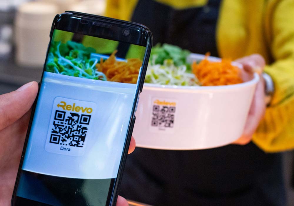 Der Barcode einer ORNAMIN To-go Mehrwegschalen im Einsatz Relevo Mehrwegsystem wird per Handy gescannt
