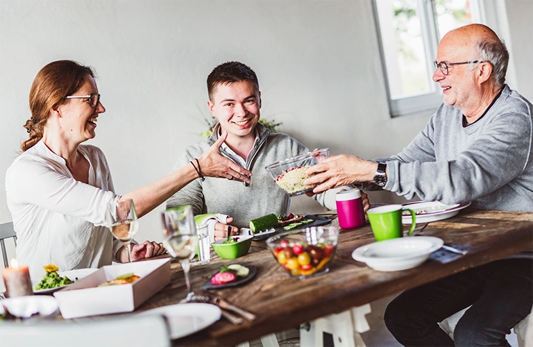 ORNAMIN-Alle an einen Tisch Drei Personen sitzen am Tisch beim Essen. Three people sit at the table eating.