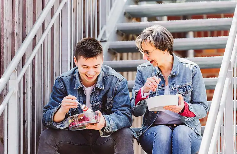 ORNAMIN-Coffee-Food-to-go ORNAMIN- zwei Personen sitzen auf einer Treppe mit Food To go Schale