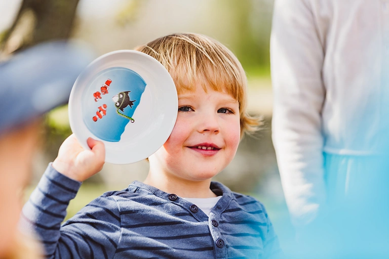 Child holds up child's plate