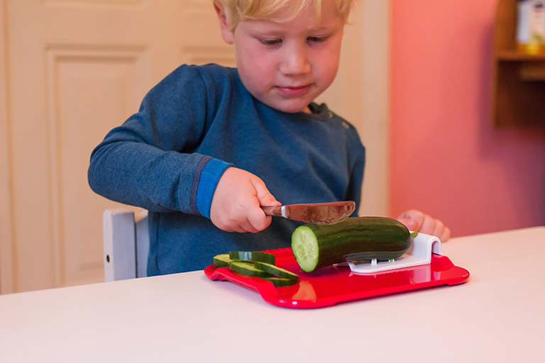 Junge schneidet Gurke mit ORNAMIN Essbrettchen