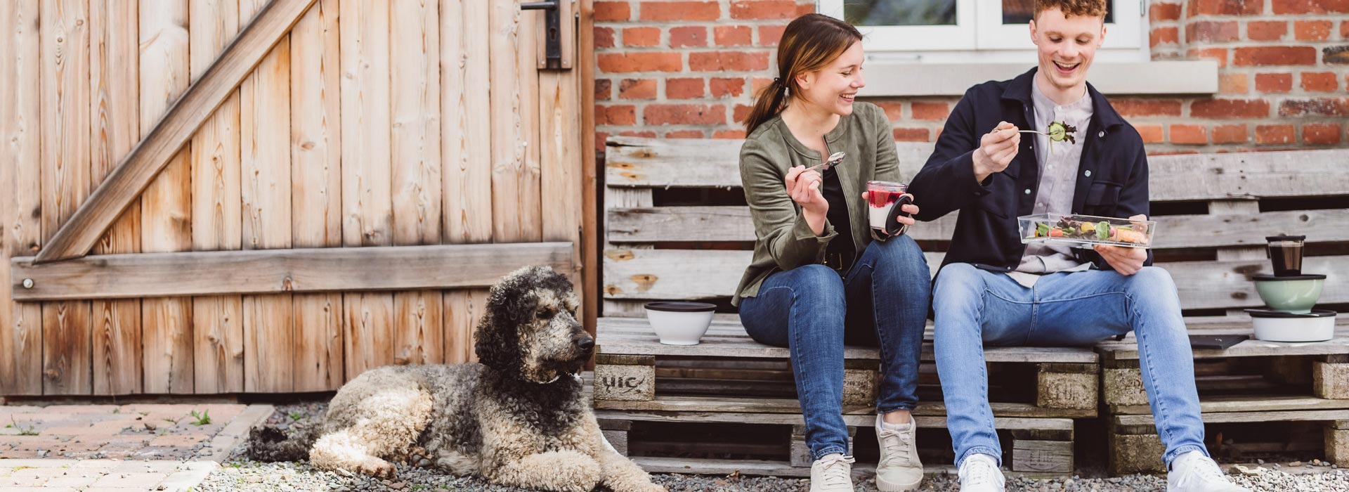 ORNAMIN-Coffee-to-go-und-Food-to-go-Geschirr Zwei junge Menschen auf einer Parkbank nutzen ORNAMIN Coffee to-go und-Food-to-go-Geschirr