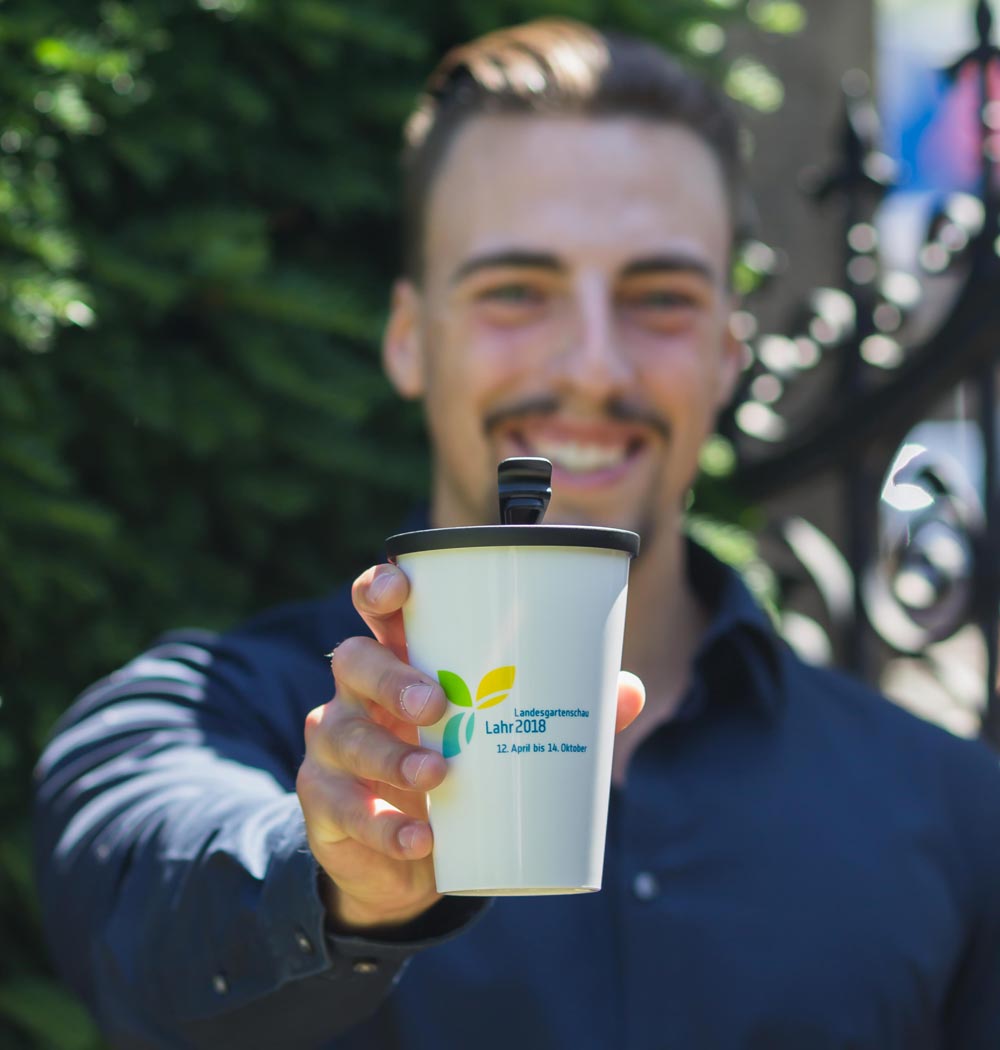 ORNAMIN Coffee to-go Mehrwegbecher im Design der Landesgartenschau Lahr wird in einer Hand gehalten