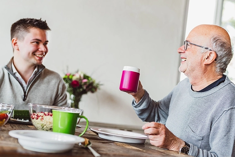 ORNAMIN-Alle an einen Tisch Ein junger und ein alter Mann zusammen am Esstisch. A young and an old man together at the dining table.