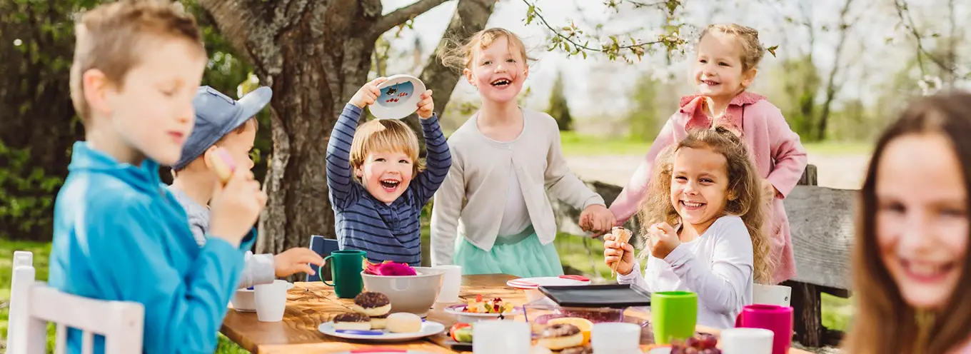Fröhliche Kinder sitzen am Tisch mit ORNAMIN Kindergeschirr