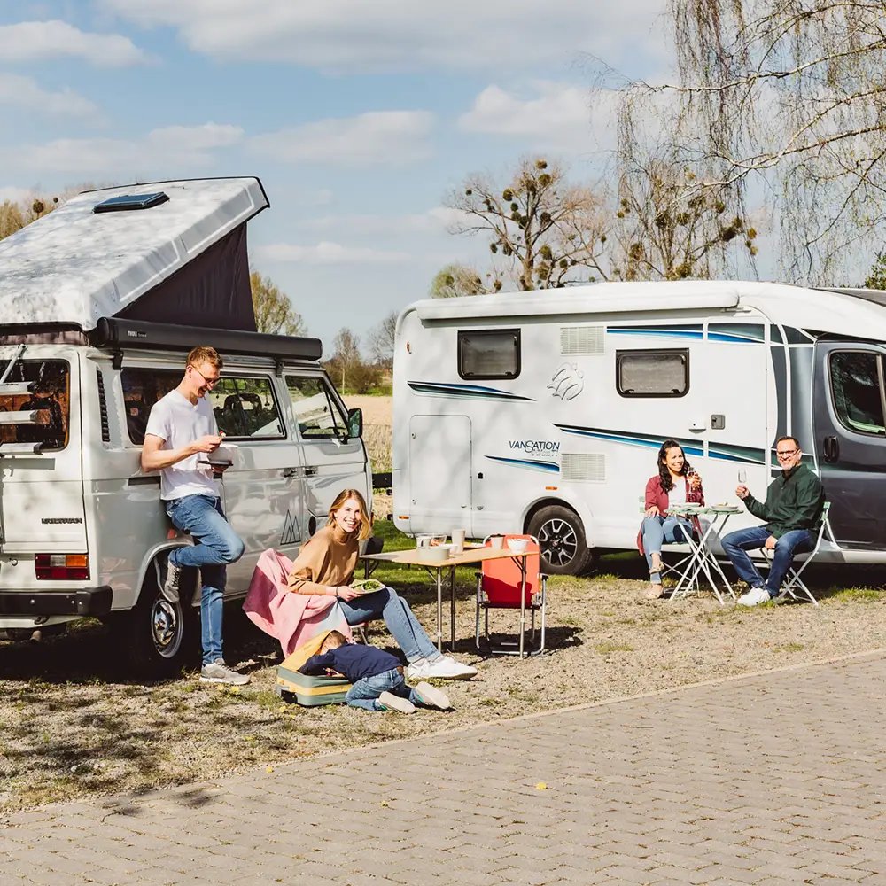 ORNAMIN-Campingwagen-Camping-1000x1000- ORNAMIN-Zwei Familien stehen vor ihren Wohnwagen