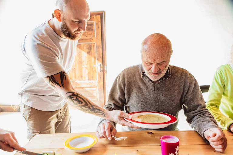 A caregiver serves a plate of soup to a patient
