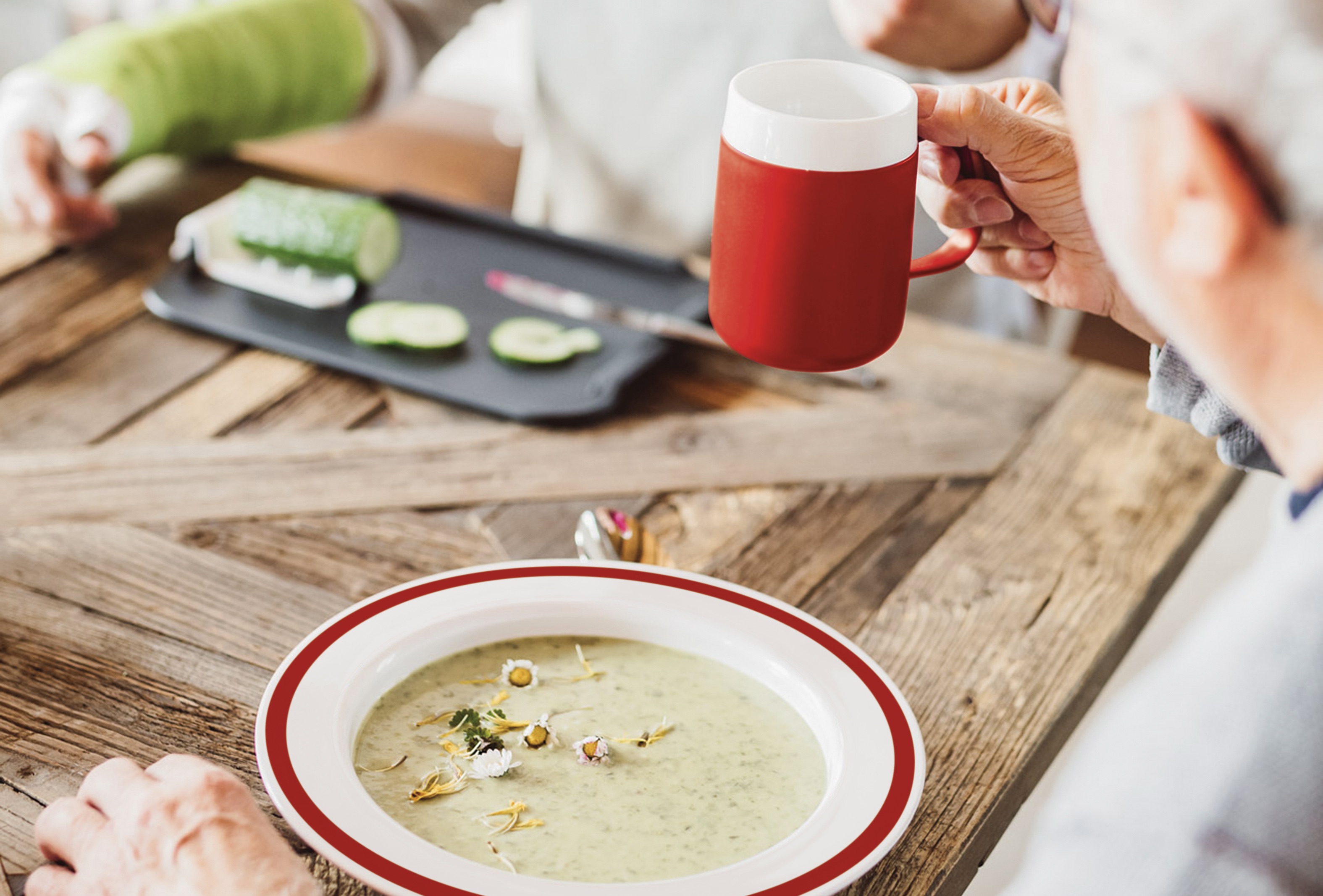 ORNAMIN-Demenzgeschirr-dementia tableware Auf dem Tisch steht ein Teller mit Kipp-Trick mit rotem Rand. On the table is a plate with special Features with a red rim.