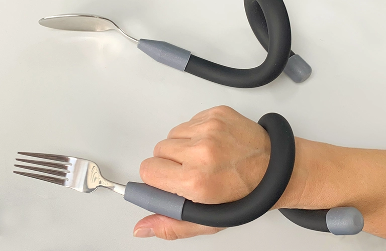 ORNAMIN-Biegsames Besteck-flexible cutlery Hand hält eine Gabel mit biegsamem verlängertem Griff. hand holds a fork with a flexible extended handle.