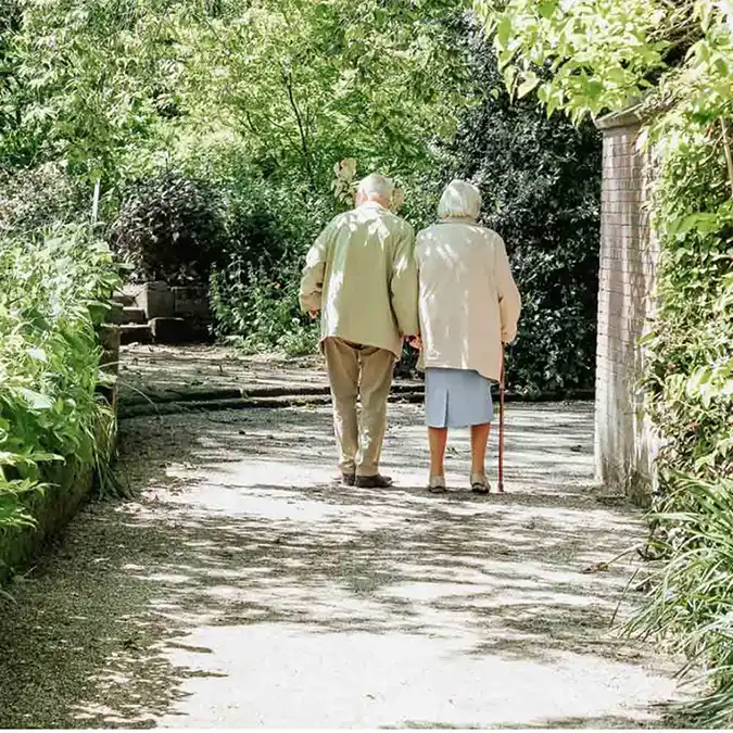 zwei ältere Menschen gehen durch einen Garten