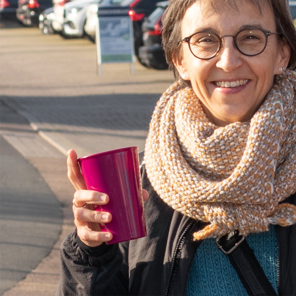ORNAMIN Coffee To go Mehrwegbecher in brombeer mit einer lachenden Frau