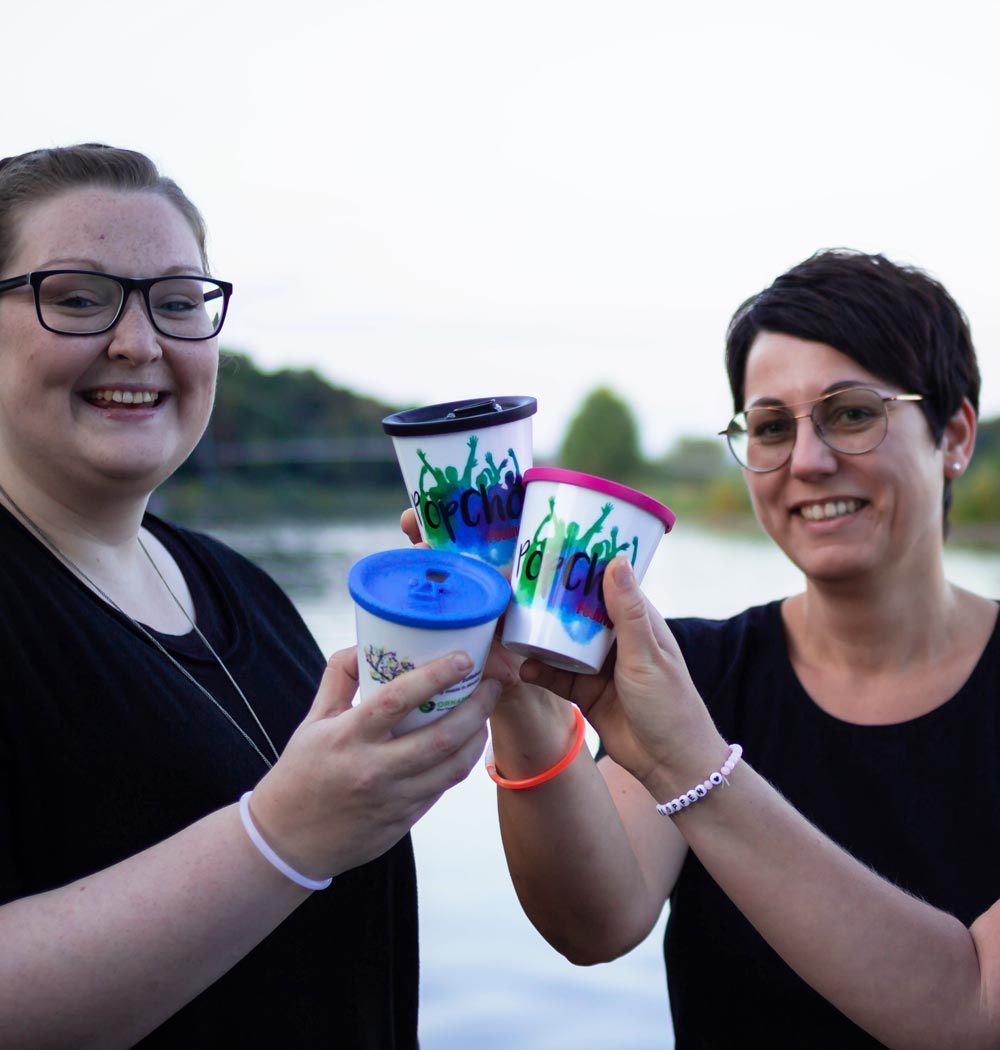 ORNAMIN-Coffee-to-go-Mehrwegbecher-Referenz-Pop-Chor-Festival Drei Personen stoßen mit ORNAMIN Coffee to-go Mehrwegbechern auf dem Pop Chor Festival an