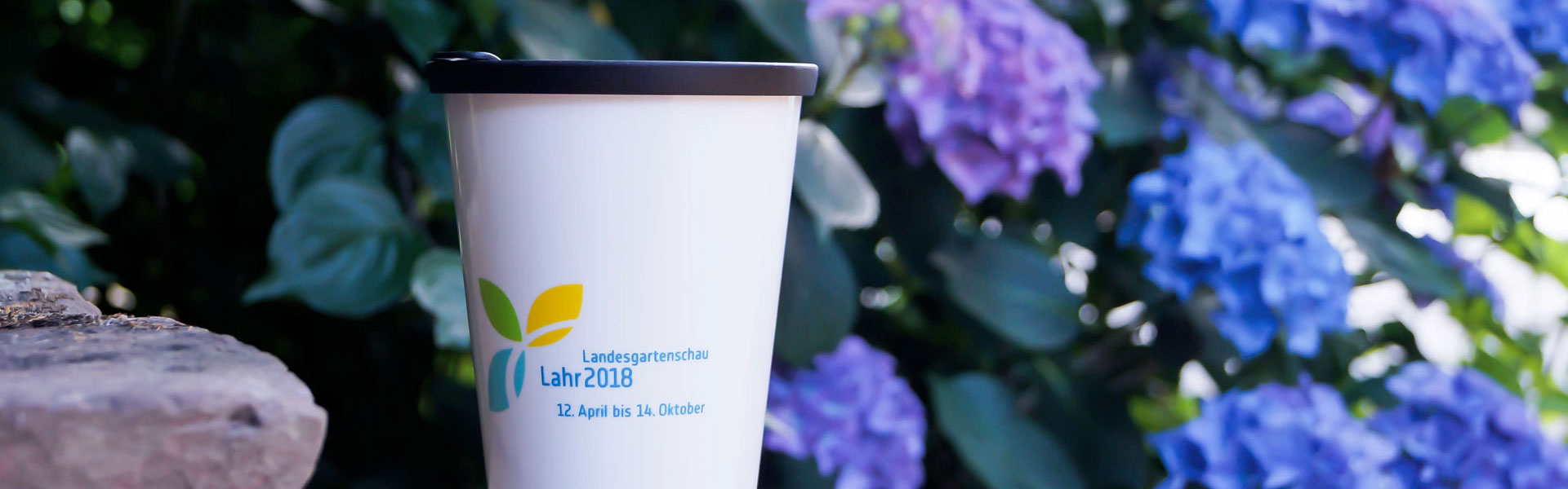 ORNAMIN-To-go Mehrwegbecher Great Gloria mit Dekor vor Blumen