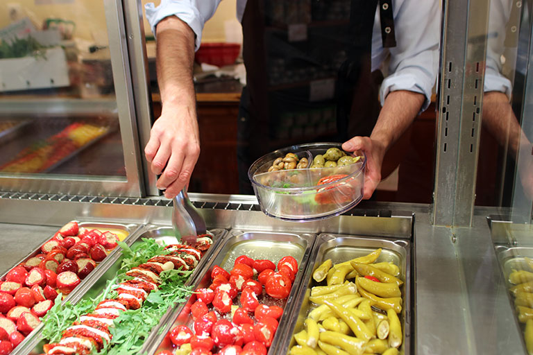 Mann befüllt ORNAMIN Schalen mit Antipasti
