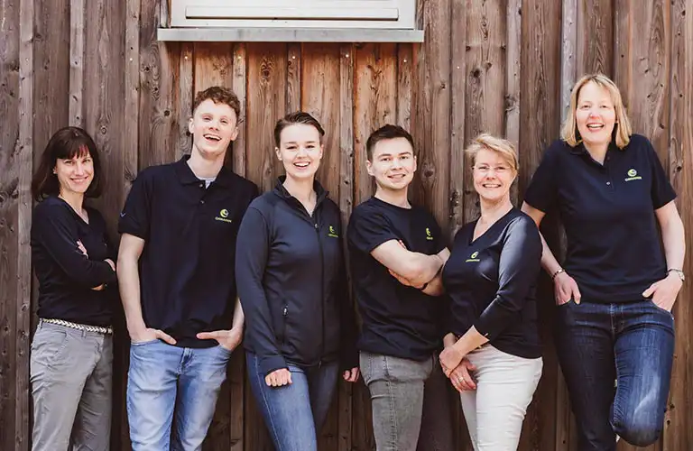 ORNAMIN-Unternehmen-Ueber-uns ORNAMIN Team lachend an einer Wand