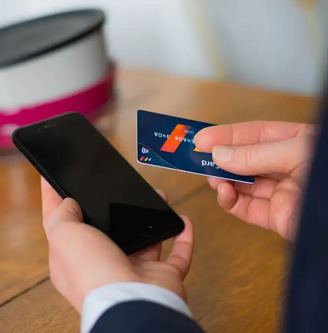 Person mit Kreditkarte und Handy prüft Zahlungsmöglichkeiten