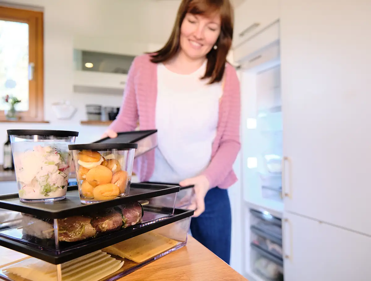 Eine Frau räumt mit Essen gefüllte Mehrwegboxen zur Aufbewahrung in den Kühlschrank