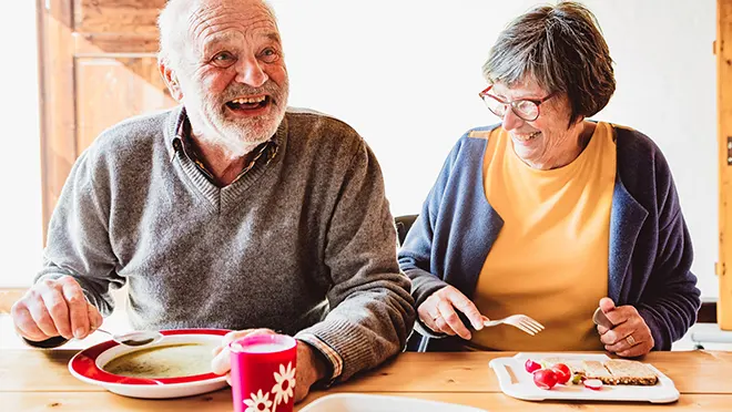 ORNAMIN-Funktionsgeschirr-für-für-Pflegeeinrichtungen Zwei Personen essen mit ORNAMIN Pflegegeschirr am Tisch