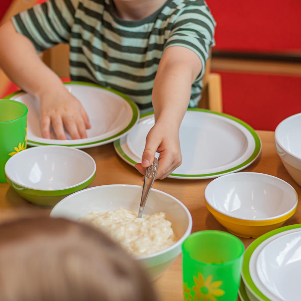 ORNAMIN Mehrweg Kinderteller Kinderschalen und Kinderbecher auf einem Esstisch in der Kita