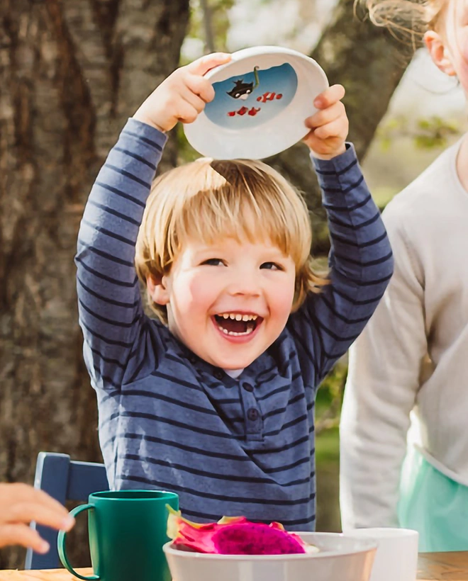 Kind hält Kinderteller hoch